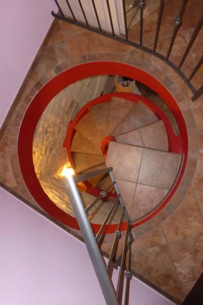 Profilo a elicoide di una scala per interni in calcestruzzo armato con ringhiera in metallo e intonaco rosso