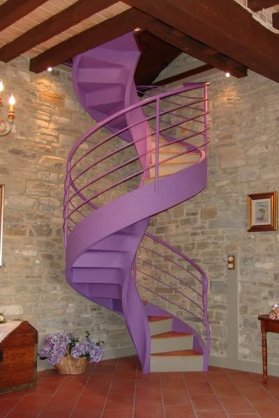 Scala a chiocciola elicoidale a Piacenza con gradini in cotto e ringhiera in ferro color viola dallo stile eccentrico