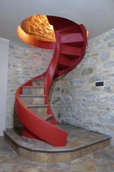 Scala elicoidale a Piacenza in calcestruzzo armato intonacato in rosso con profilo dei gradini a vista senza parapetto