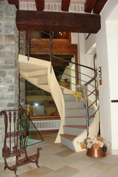 Scala elicoidale per interni a Piacenza in cemento armato con gradini in cotto e ringhiera in acciaio zincato