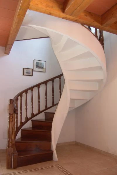 Scala per interni classica con struttura in cemento armato intonacato in bianco e ringhiera in legno sagomato in provincia di Piacenza